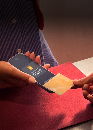 Una mano che appoggia una carta di credito a un iPhone per completare una transazione